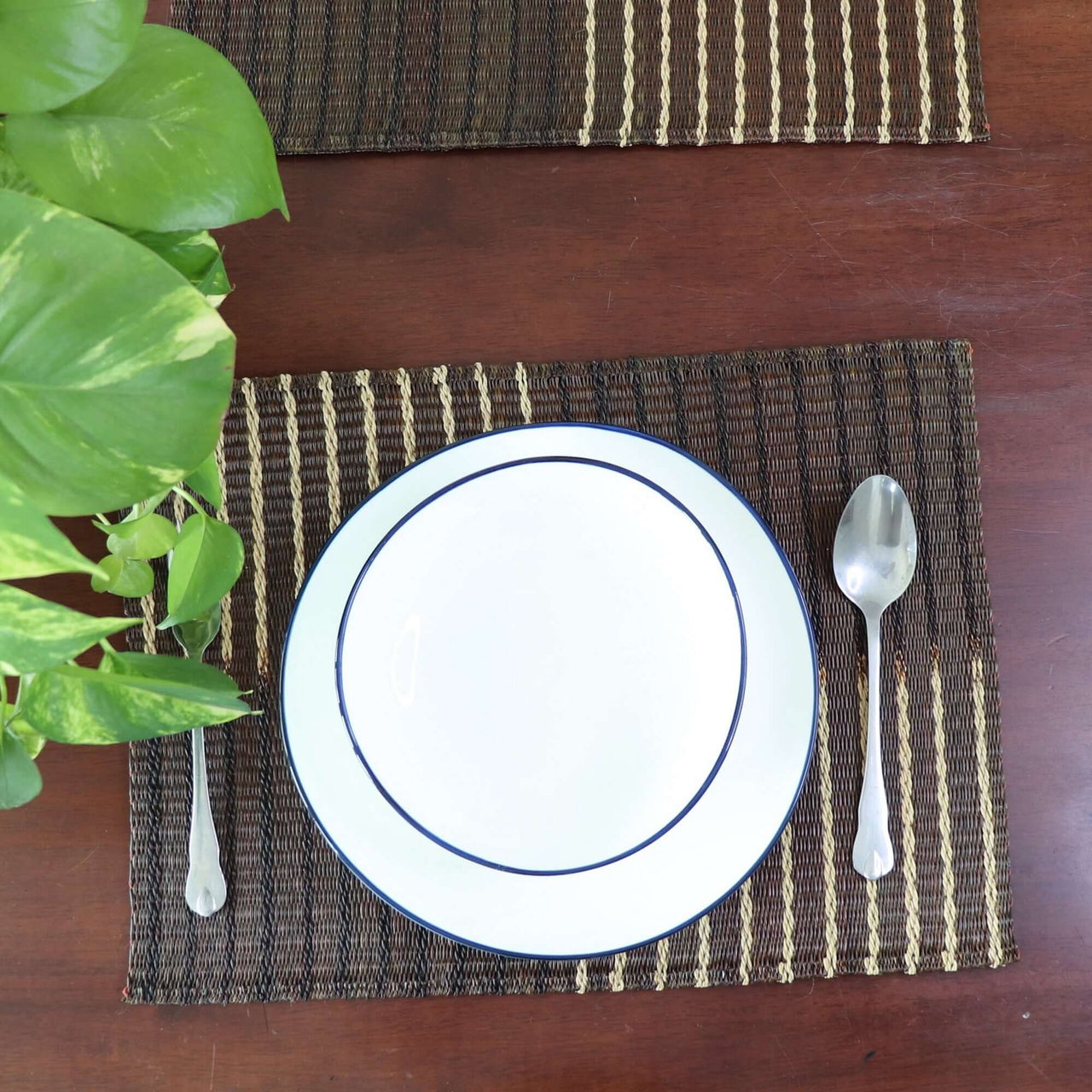 Placemat with a plate, spoon, and knife on a wooden table.