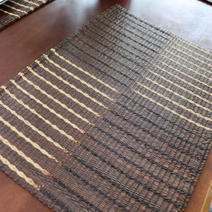 Textured brown and beige woven mat on a wooden surface