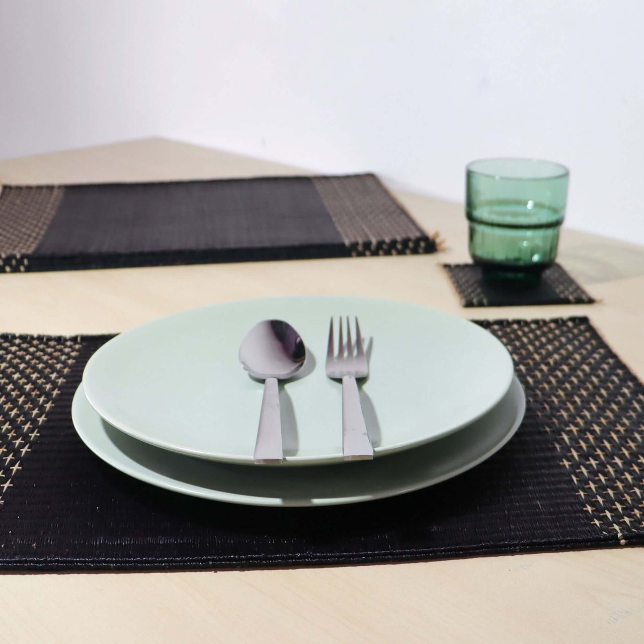 Lavila Handwoven Placemat with modern table setting featuring green plates and cutlery.