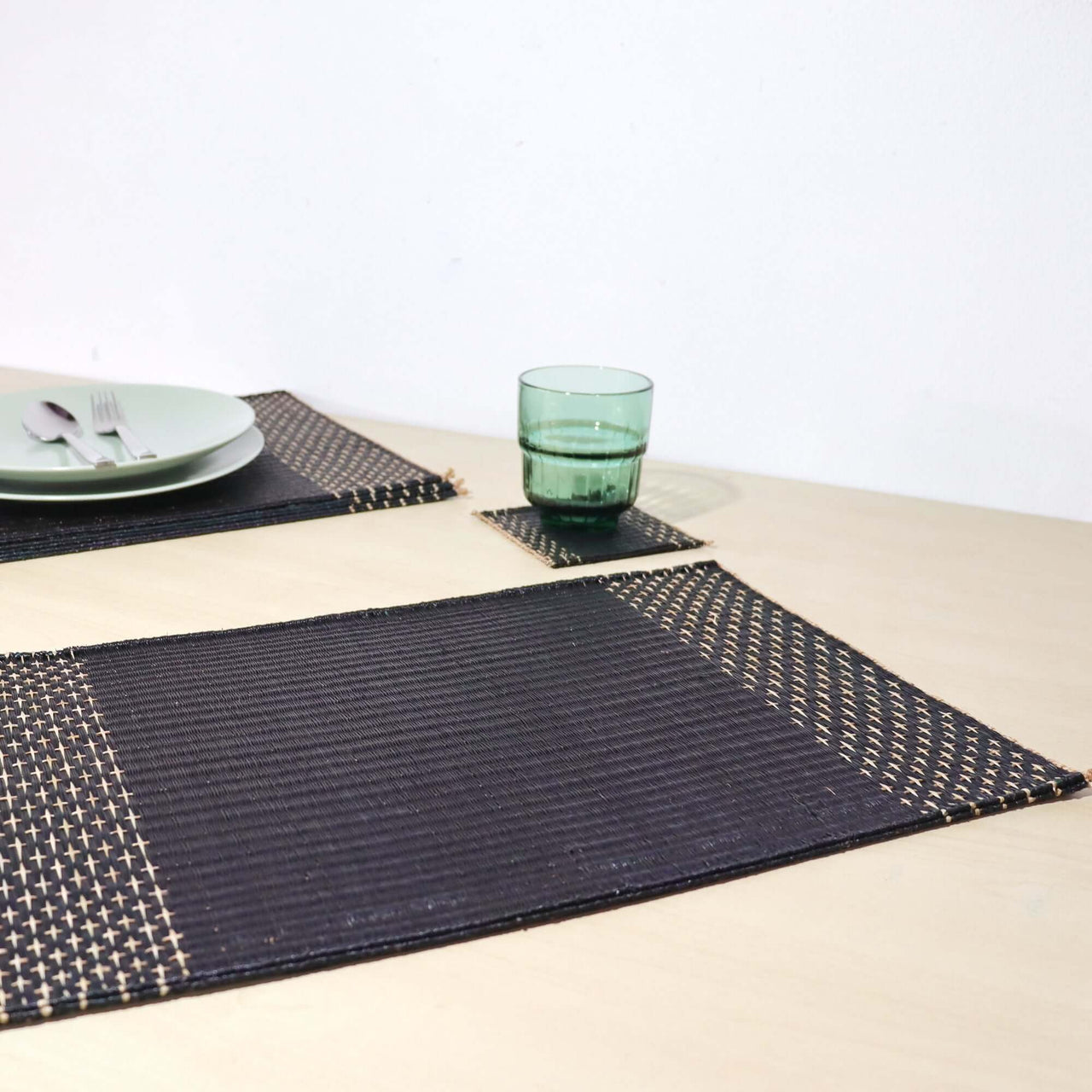 Lavila Handwoven Placemat showcasing elegant black tone and natural edging on a minimalist dining table.