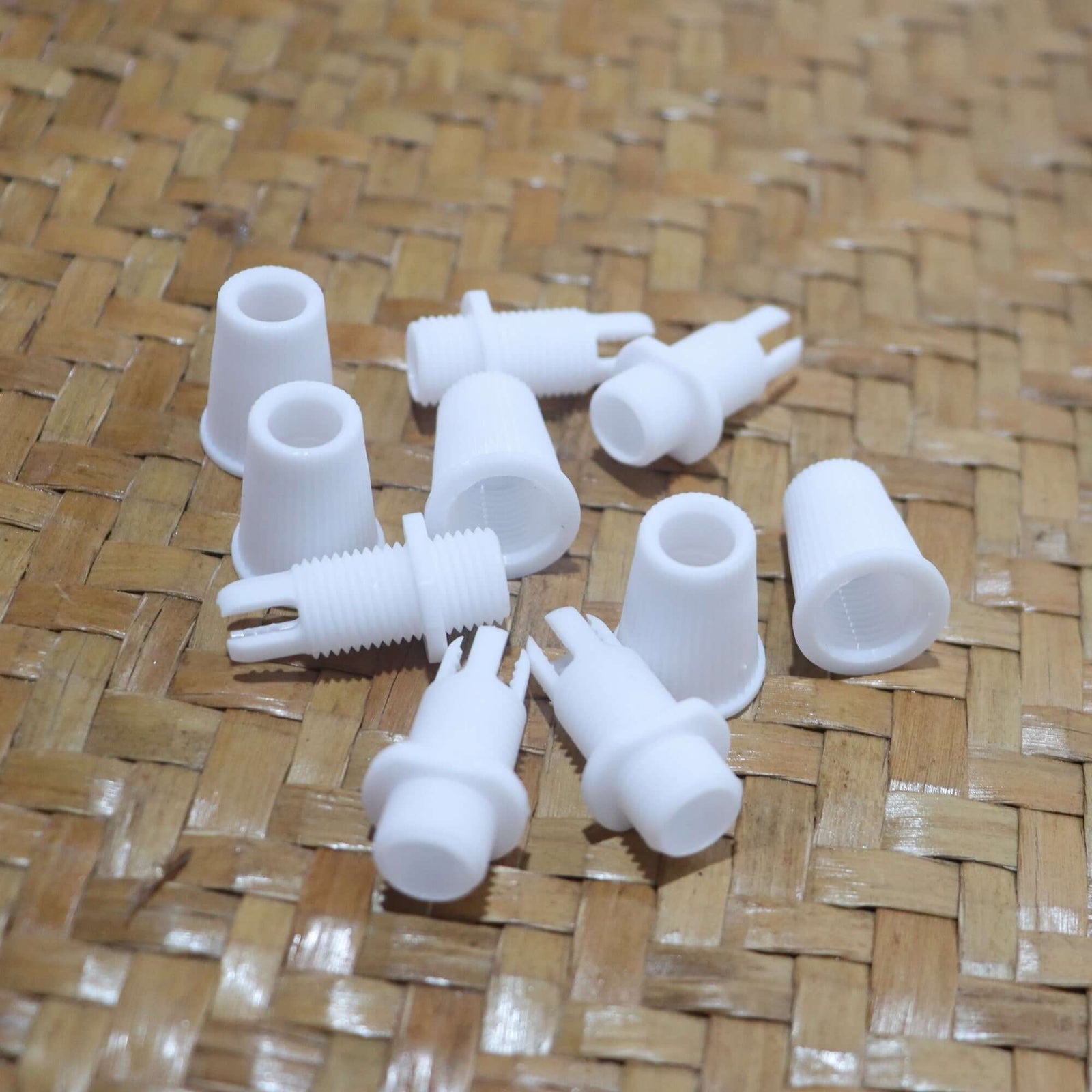 White Cord Grips Lampshade Holder – Plastic Screw Style Cord Grip (20 pcs.) arranged on woven surface.