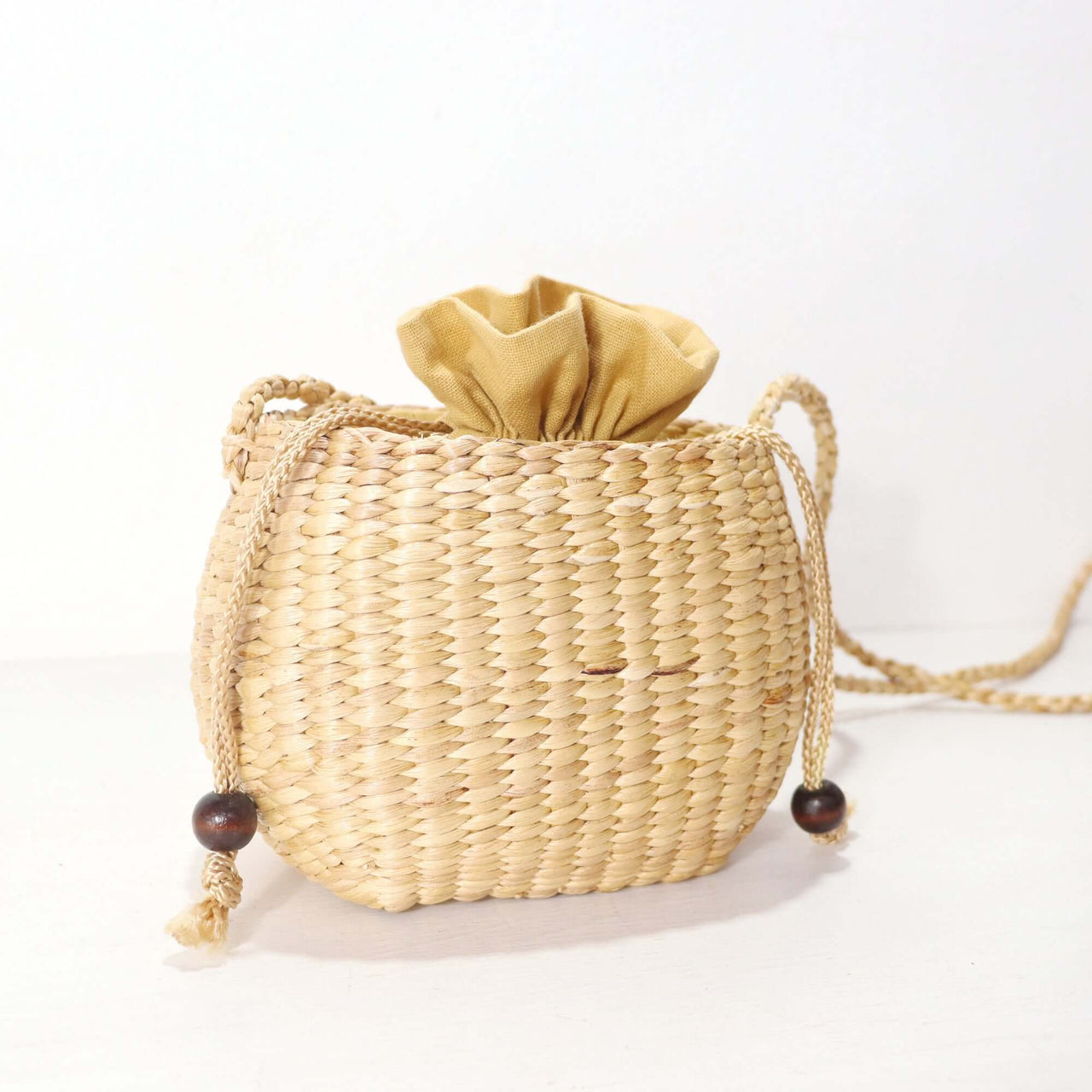 WANAREE - Cross Body Bag in natural woven material with a golden fabric drawstring top, perfect for everyday use.