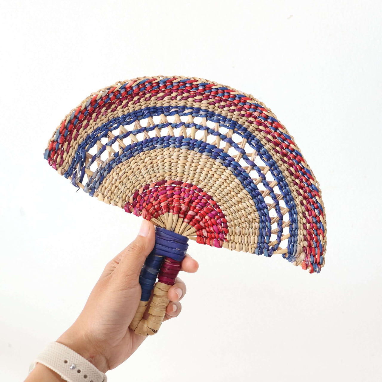 LA LA VAN – Handwoven Fan (Wall Hanging & Hand Fan) held by a person showcasing vibrant multicolour patterns.
