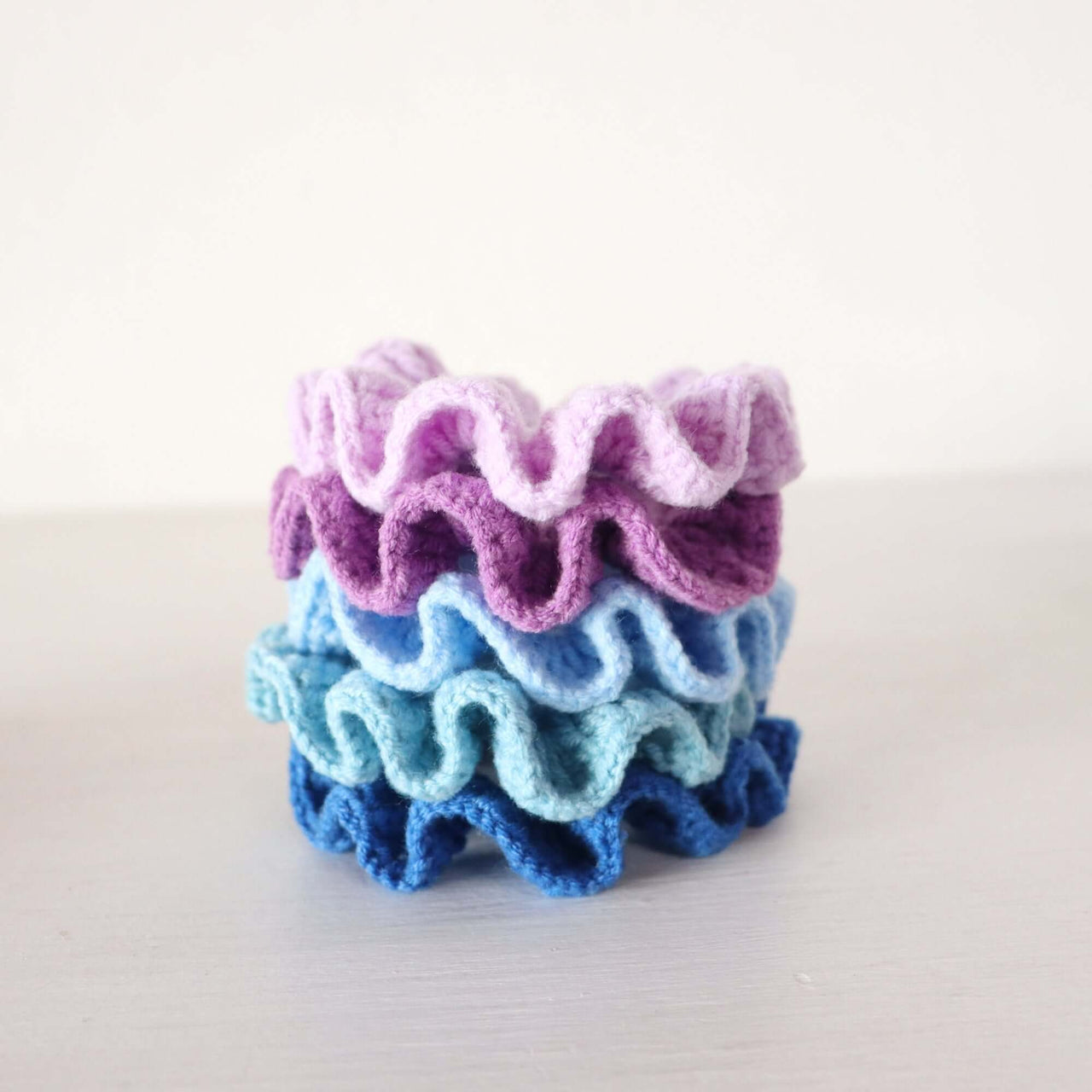 Purple Tones - Hand Crochet Scrunchies in soft purples and blues stacked together on a light background.