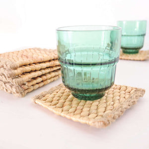 KA NOK PUN Water Hyacinth Boho Coaster Set of 4 with green glasses on rustic coasters, showcasing natural texture.