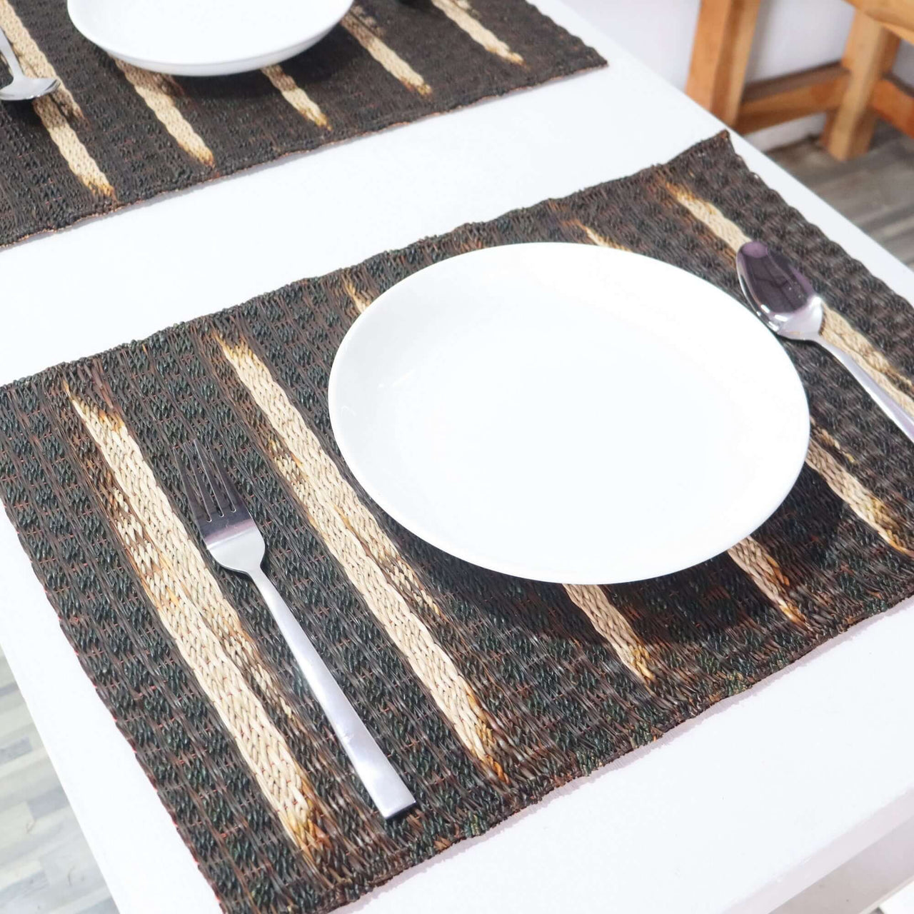 Placemat with striped pattern on a table setting with a plate, fork, and spoon.