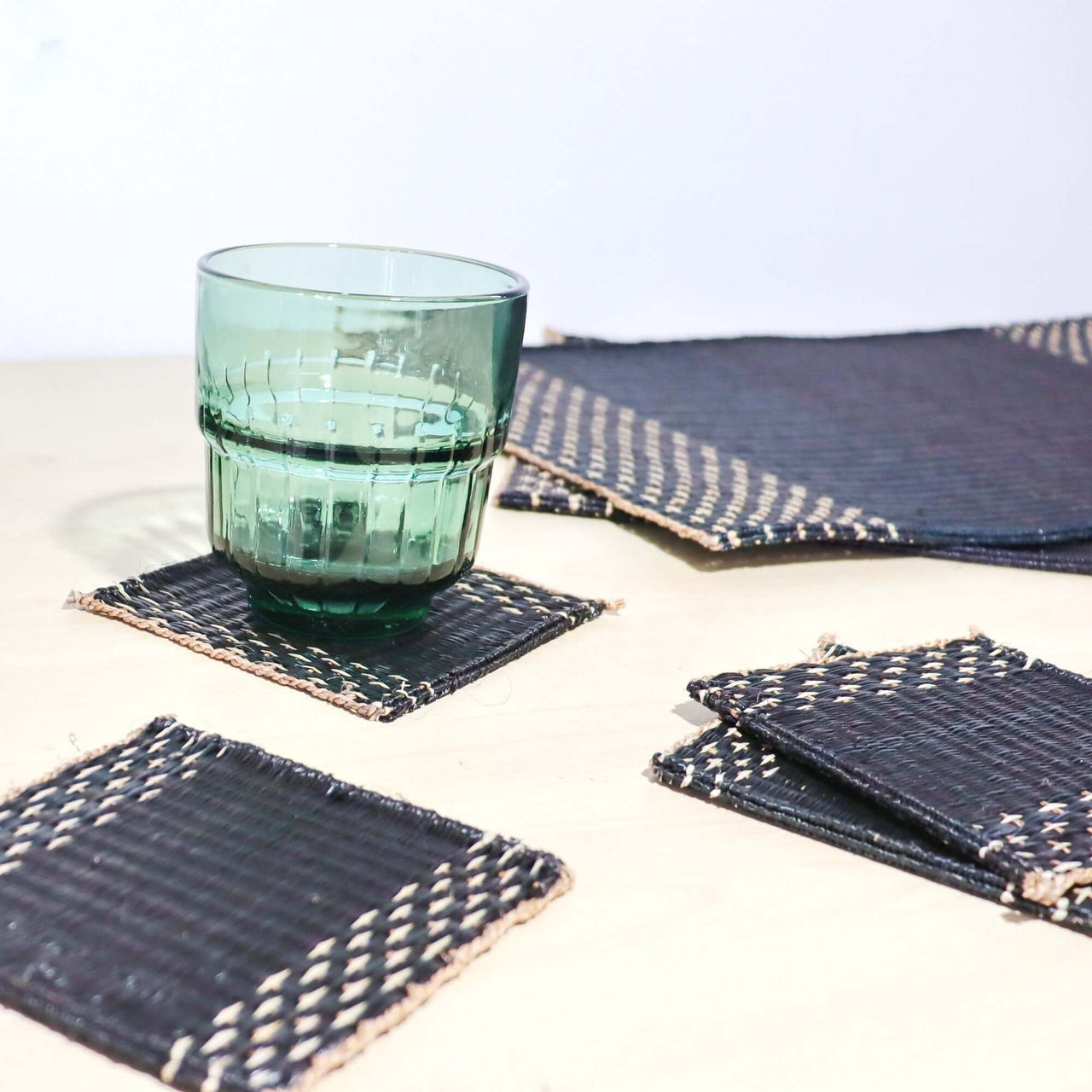 Lavila Handwoven Coaster Set of 4, featuring black woven center and natural edge, perfect for modern interiors.